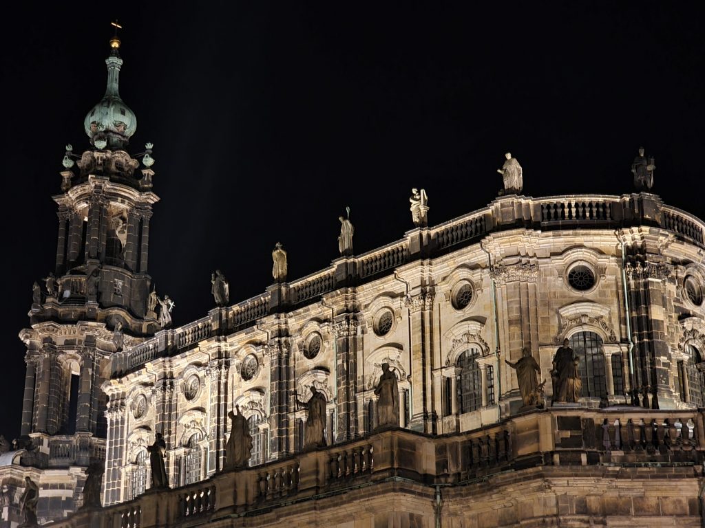 A baroque building in the historical city of Dresden, lit up during the night. The former stone bricks blackened by fire are combined with new elements