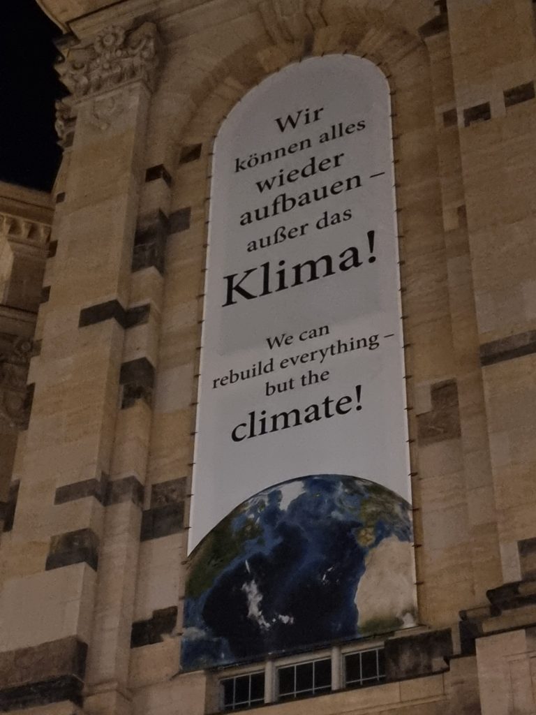 A banner hung on a historical building, that says "We can rebuild everything - but the climate!"