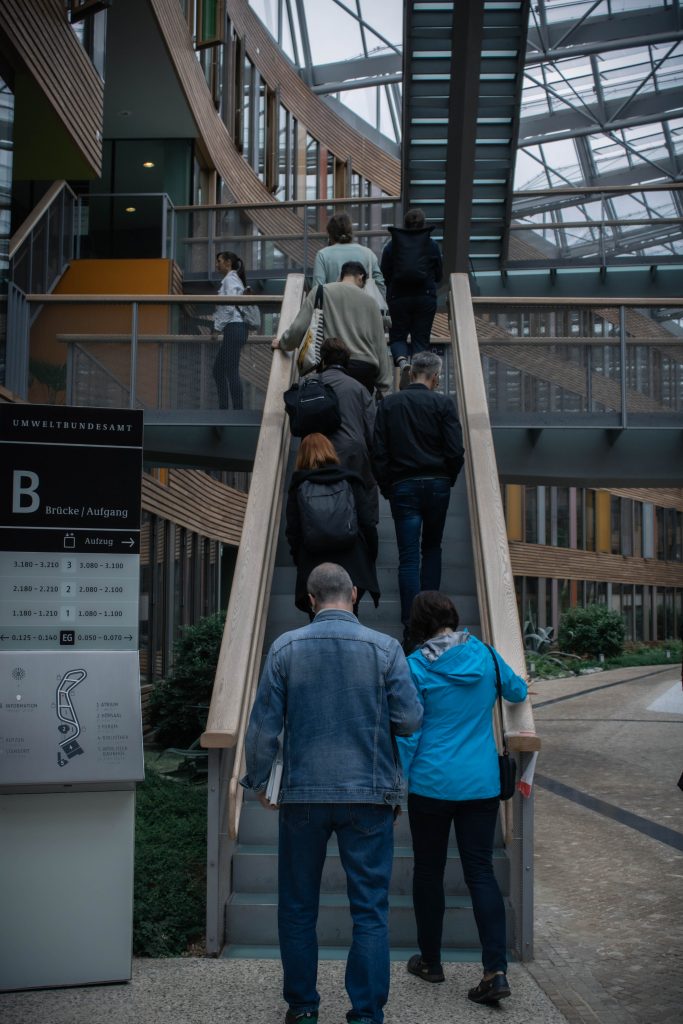 A group of people walking up the stairs inside a spacious atrium, which creates an indoor street