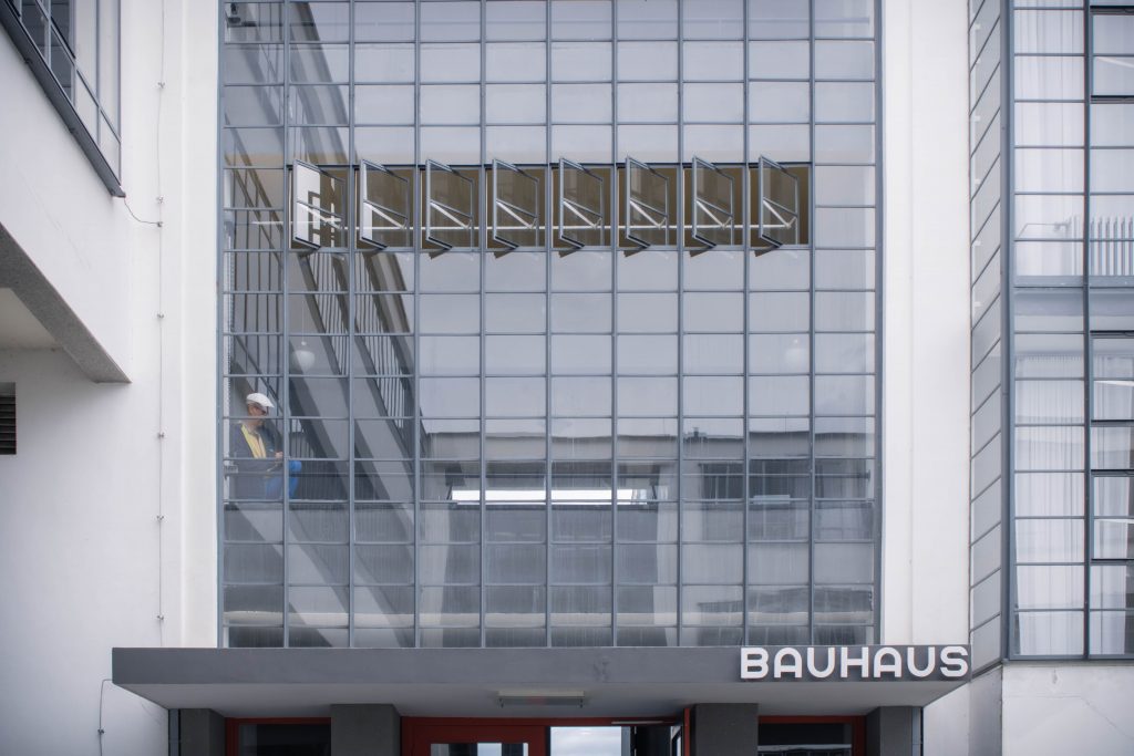 An artist sits and draws behind the glass facade above the Bauhaus entrance