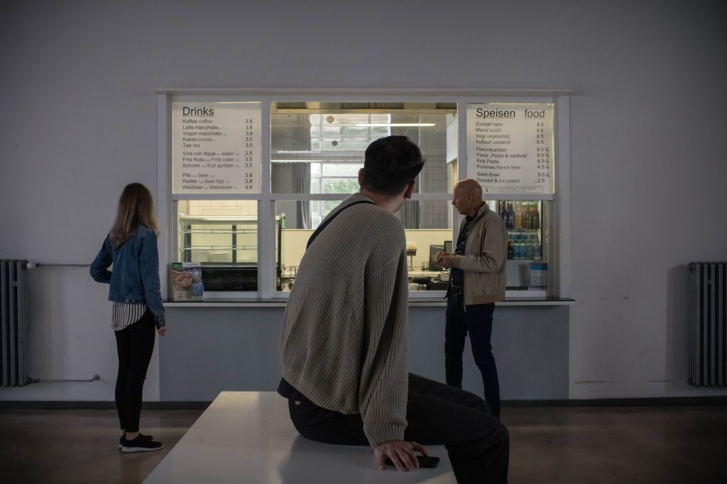 Visitors looking at the serving window of a former cantine, which is still used