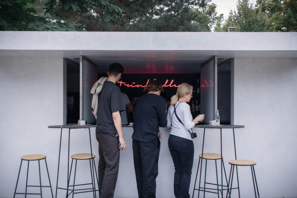Visitors buying coffee in the window of a architecturally minimalist kiosk